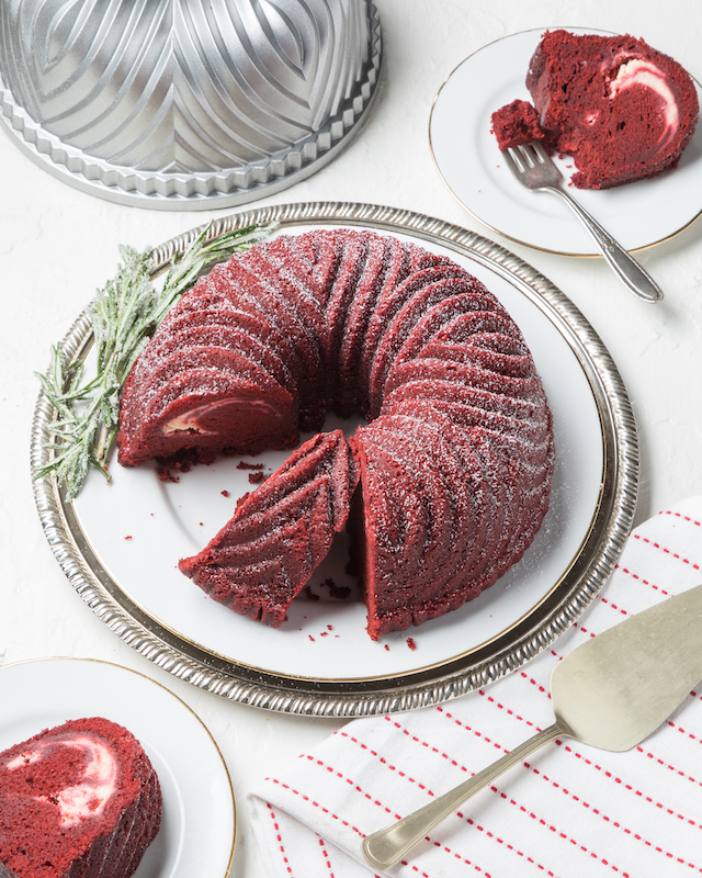 Red Velvet Bundt Cake on white platter with rosemary