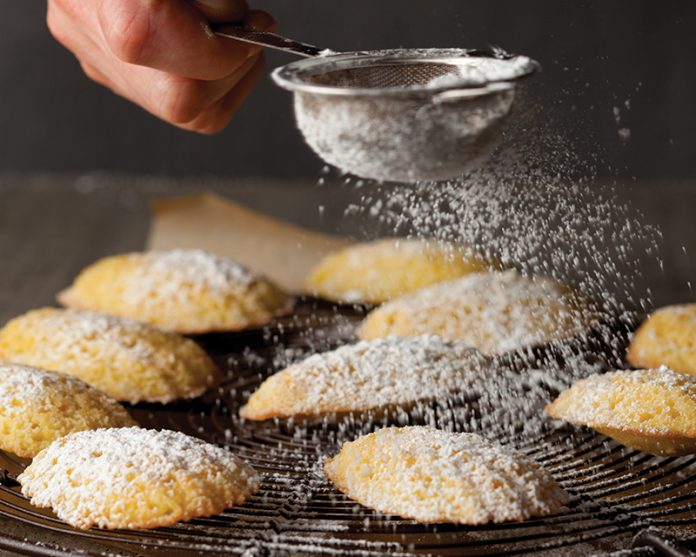 Tangerine Madeleines on wire rack with confectioners sugar