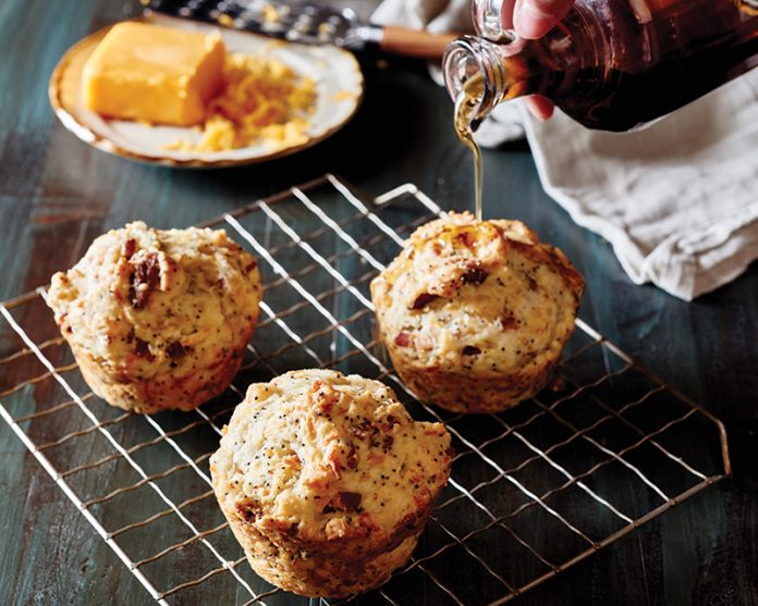 Bacon Cheddar Poppy Seed Muffins on wire rack with pouring syrup