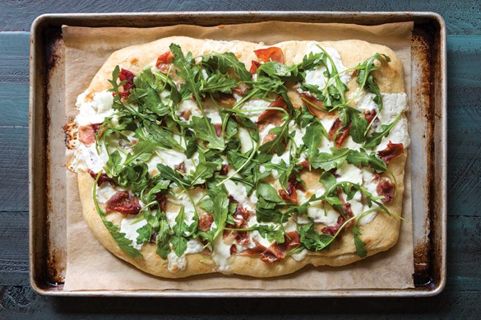 Focaccia with Burrata, Prosciutto, and Arugula on sheet pan with parchment
