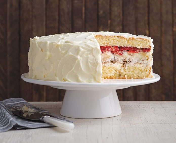 Pecan Meringue Cake on white cake stand sliced