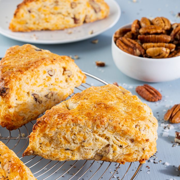 Black Pepper, Cheddar, and Pecan Scones on wire rack on blue surface