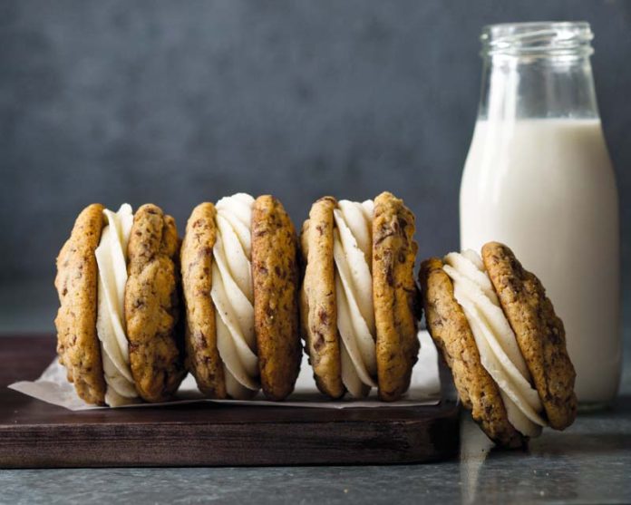 four chocolate chip graham sandwich cookies with glass of milk